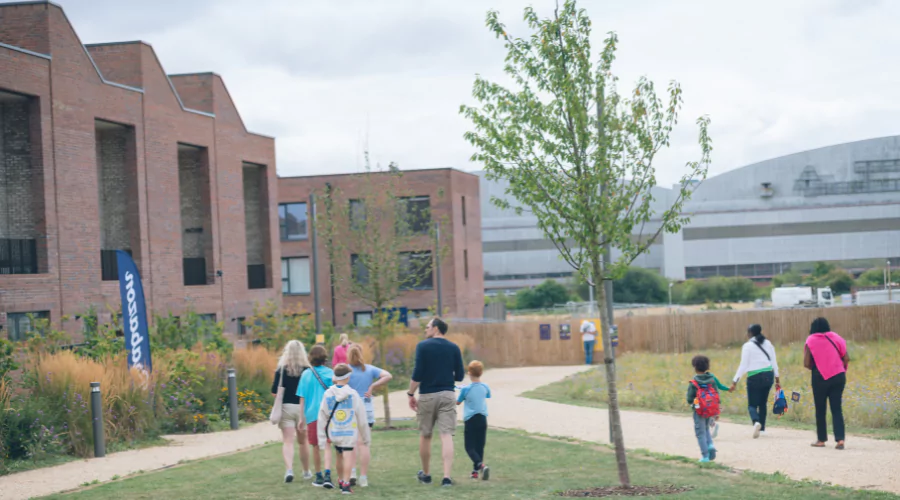 Families walking through a green space in front of the new homes at Brabazon in Bristol.